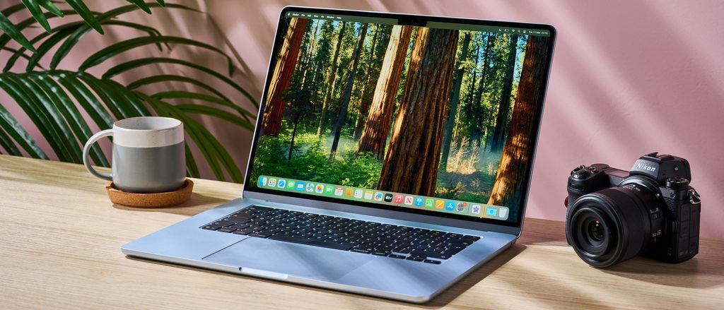 Silver Apple MacBook Air 15 laptop open on a wooden table next to a camera and mug