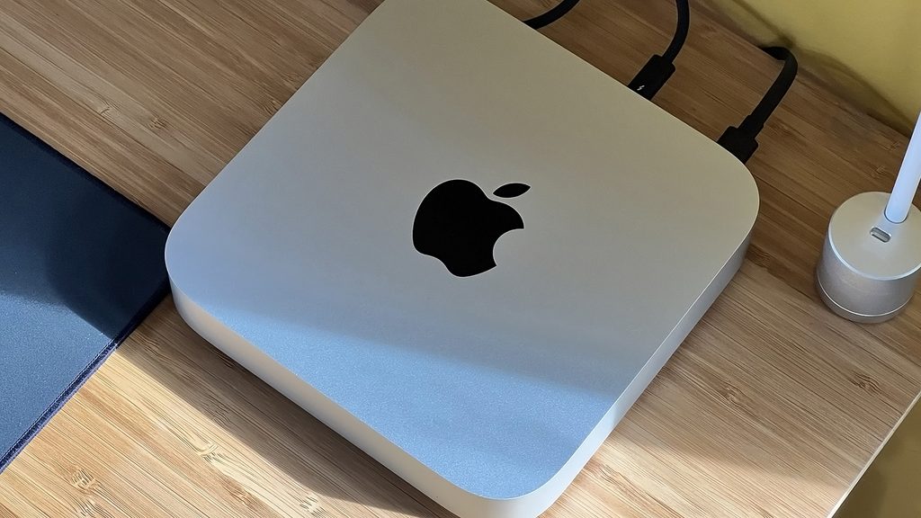 Silver Apple Mac mini desktop positioned next to its official white retail packaging box